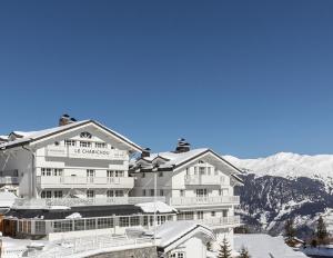 谷雪维尔勒查比措酒店的一座白色的大酒店,背景是积雪覆盖的群山