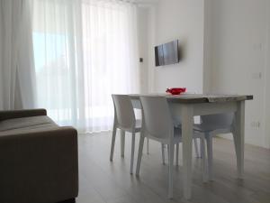 利多迪耶索罗Jesolo Appartamenti F2 - Coral Red的餐桌、白色椅子和电视