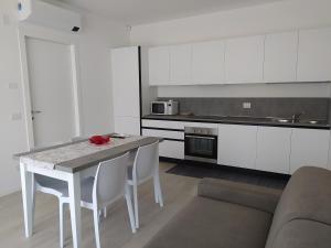 利多迪耶索罗Jesolo Appartamenti F2 - Coral Red的白色的厨房配有桌子和白色椅子