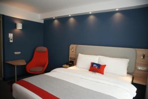 吕姆朗Holiday Inn Express Zürich Airport, an IHG Hotel的酒店客房,配有一张床和一张红色椅子