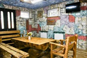 库塔伊西Mango's Guesthouse的一间设有木桌和石墙的客房