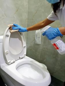 北标府Hotel Chuan Chom The High Resort Saraburi - SHA Plus的戴蓝色手套的女人正在清洁厕所