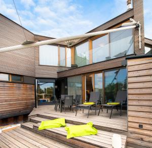 滨湖新锡德尔Seehaus SeeZeit - Am Hafen的房屋设有木甲板,配有桌椅