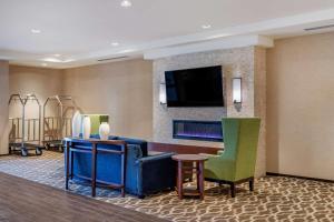 ClarkstonComfort Inn & Suites的酒店客房带大堂,带电视和椅子。