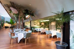 巴塞罗那巴塞罗那雅典娜公寓式酒店的餐厅拥有白色的桌椅和棕榈树