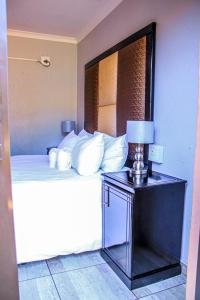 索赫燕杜Thavhani Guest House的一张带白色枕头的床和一张桌子上的台灯