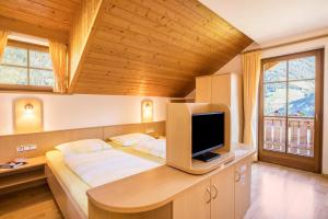 卡迪皮特拉Kuglerhof Apt 2的一间卧室配有一张床铺,书桌上配有电视