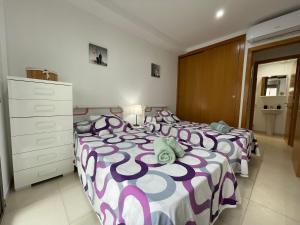 阿尔库迪亚港Samsara Beach的一间卧室配有两张紫色和白色床单