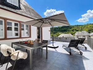 摩泽尔河畔的泽尔Villa Burglay的庭院配有桌椅和遮阳伞。