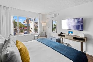 圣地亚哥Sea Harbor Hotel - San Diego的一间卧室配有一张床、一张书桌和一个窗户。