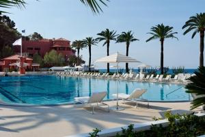 罗克布吕讷-卡普马丹蒙特卡洛海滩酒店的一个带椅子和棕榈树的大型游泳池