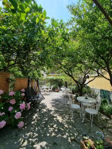 莱圭利亚Villa Pina的庭院设有桌椅,种有树木和鲜花
