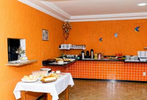 瓜拉派瑞Pousada da Zezé的橙色的厨房,配有两张桌子和食物