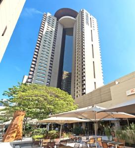 圣保罗Staybridge Suites São Paulo, an IHG Hotel的两座高大的建筑,在庭院里配有桌子和遮阳伞