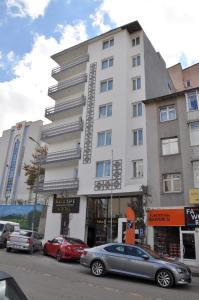 埃尔祖鲁姆SAKA LİFE OTEL的一座白色的大建筑,前面有汽车停放