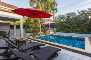 奥南海滩Honeybee Pool Villa Smooth as Silk的一个带红色遮阳伞和椅子的游泳池