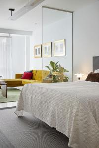 圣塞瓦斯蒂安Satori Suites的一间卧室配有一张大床和一张黄色的沙发