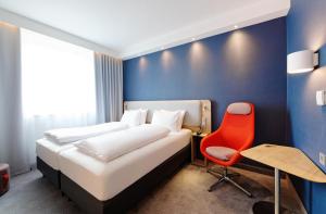 卢斯特瑙Holiday Inn Express - Lustenau的一间卧室配有一张床和一张红色椅子