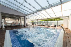 坎帕斯蒂利亚诺蒂卡酒店的一个带玻璃天花板的游泳池和一个室内游泳池