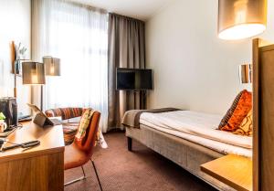 尼雪平斯堪迪克大酒店的配有一张床和一张书桌的酒店客房
