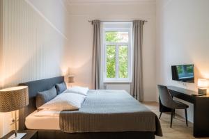 威斯巴登奥罗拉酒店的一间卧室配有一张床、一张书桌和一个窗户。