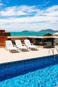 弗洛里亚诺波利斯Ilhasul Hotel Residencia的一个带躺椅的游泳池和海洋