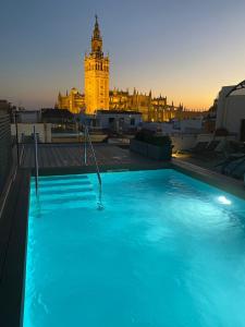 塞维利亚Joya del Casco Boutique Hotel by Shiadu的一座带钟楼建筑屋顶上的游泳池