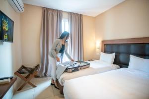 丹吉尔北星酒店的站在酒店房间两张床旁的一位女性