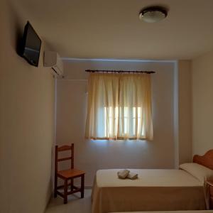 贝纳卡松Hospedaje Benacazon A49的一间卧室配有一张床和一个带椅子的窗户