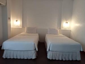 华欣BaanBusarin Hotel的配有白色墙壁的小客房内的两张床