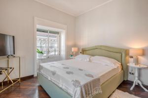 米兰Imperiale Suites Milano的一间卧室配有一张床、一台电视和一个窗口