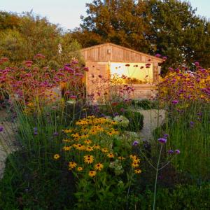 ColkirkThe Oaks Glamping - Rubie's Shepherds Hut的木棚前种满鲜花的花园