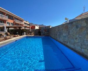 圣尼科拉斯村Hotel La Aldea Suites的蓝色海水和石墙的游泳池