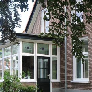 KamperveenAppartement 'Wij en de Zande'的一间有白色窗户和黑色门的房子