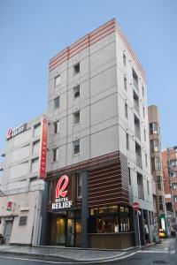 北九州小仓站瑞丽芙酒店的城市街道上的一座建筑,有商店
