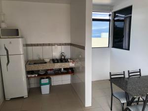 帕罗卡Apartamento Ilha do Coral的厨房配有冰箱、桌子和窗户。