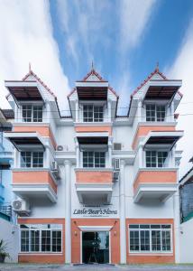 清迈小熊之家旅馆的一座白色的大建筑,带有橙色的点缀