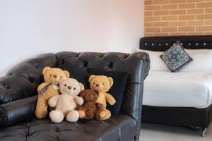 清迈小熊之家旅馆的坐在皮沙发上的三只泰迪熊