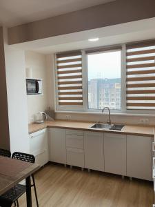 切尔卡瑟Апартаменты на Гагарина的厨房配有白色橱柜、2扇窗户和水槽