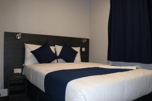 伦敦Blue Sapphire Hotel的一间卧室配有一张带蓝白色枕头的大床