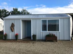 布伦海姆Vineyard Cottage in Blenheim on the Golden Mile的白色的棚子,有窗子和盆栽植物