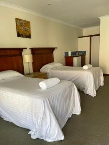 丹马克Denmark Hotel的酒店客房,配有3张带白色床单的床