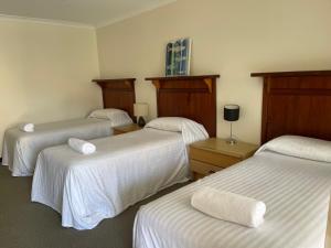 丹马克Denmark Hotel的酒店客房,配有3张带白色床单的床