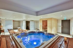 梅尔维尔弗朗瑟维尔普拉格Hôtel & Spa FACE À LA MER的铺有木地板的客房设有一个大型热水浴缸。