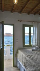 KástronMilos By The Sea - Eco House的一间卧室设有一张床和两个海景窗户。