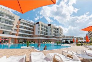 阳光海滩Grand Kamelia Holiday Apartments的酒店游泳池配有白色椅子和遮阳伞