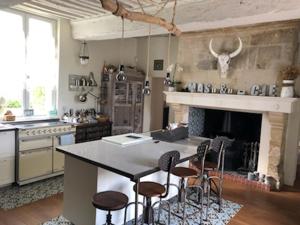 梅尔维尔弗朗瑟维尔普拉格Domaine "Les Bois Flottes" dans Maison de Charme au bord de mer et proche de Cabourg的厨房配有带凳子的柜台和壁炉。