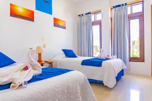 比亚米尔港Gran Hostal Tintorera的一间卧室配有两张带白色和蓝色床单的床