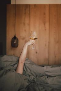 Cornedo all'IsarcoPitzner - Winery & Suites的把一杯葡萄酒藏在床上的人