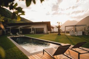 Cornedo all'IsarcoPitzner - Winery & Suites的后院设有游泳池、两把椅子和房子